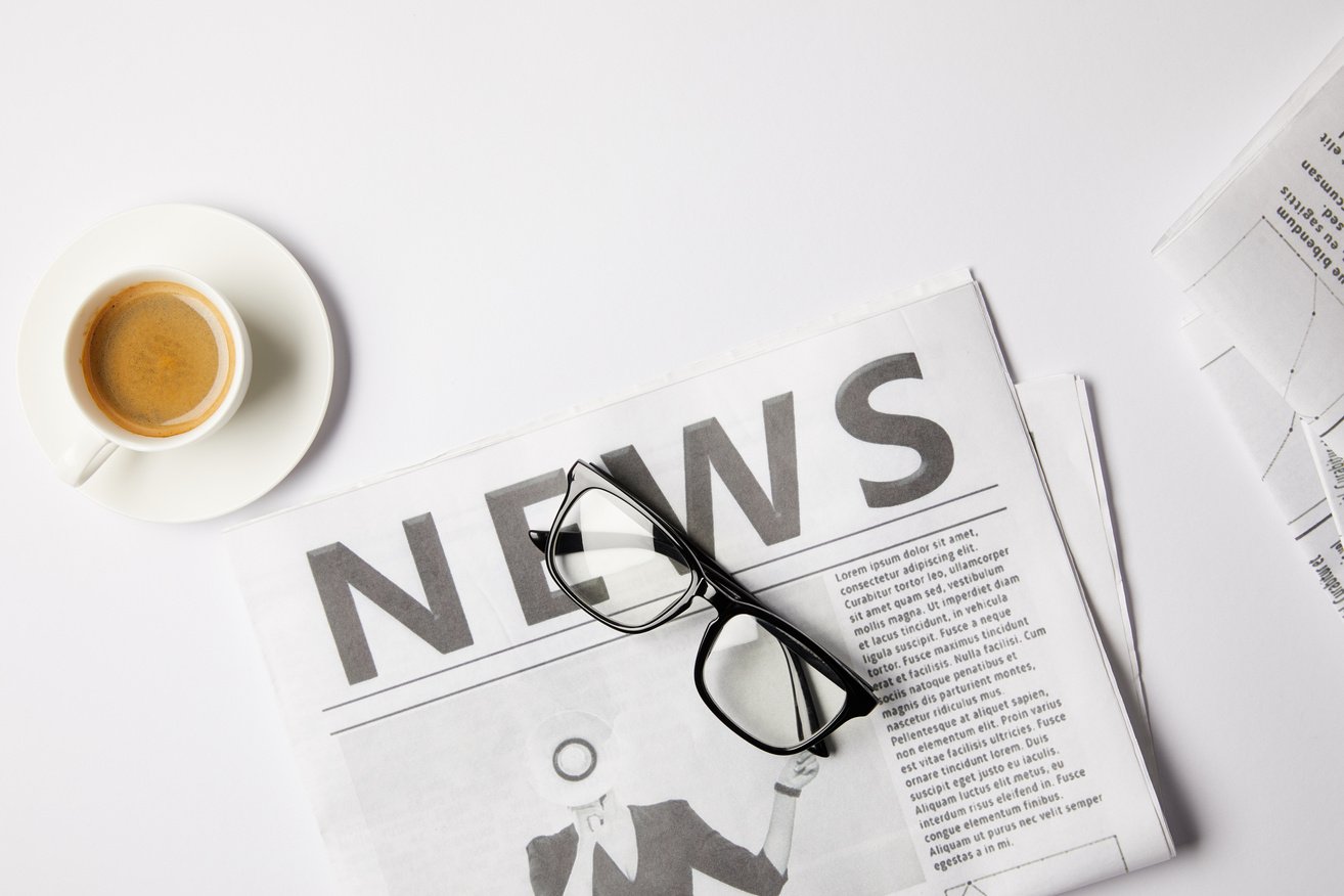 flat lay with eyeglasses, cup of coffee and newspapers, on white table